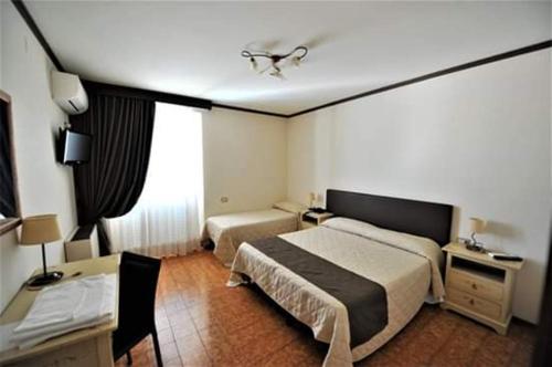 a hotel room with two beds and a desk at Hotel Il Cammino Di Francesco in Bastia Umbra