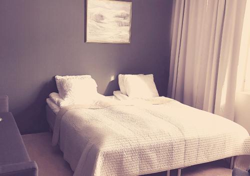 a bed with white sheets and pillows in a bedroom at Hotell Klimpfjäll in Klimpfjäll