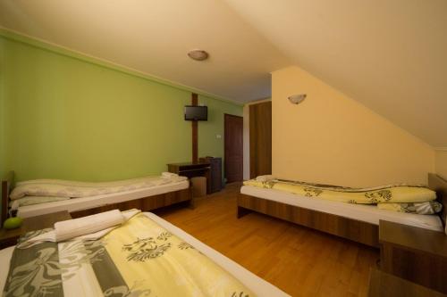 two beds in a room with green walls at Bíbic Vendégházak in Nagybajom
