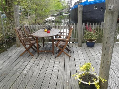 una mesa de madera y sillas en una terraza de madera en Houseboat Vliegenbos, en Ámsterdam