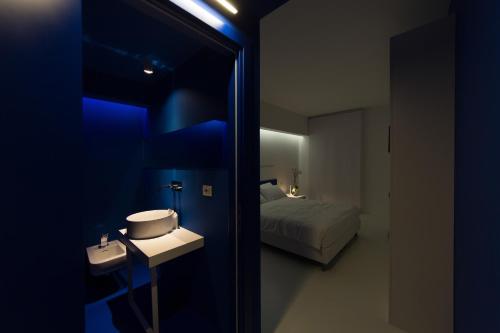 Habitación azul con cama, lavabo y espejo. en Bed 'n Design, en Floridia