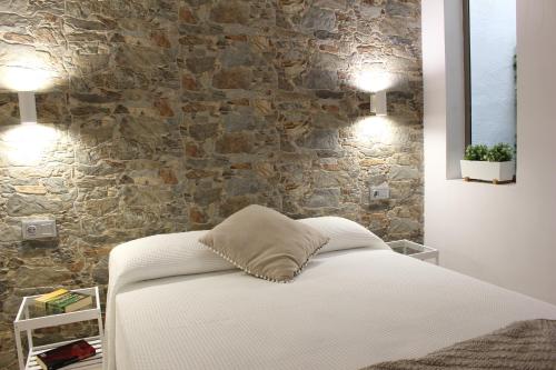 a bedroom with a bed and a stone wall at Gáldar, habitación privada en la playa in Gáldar