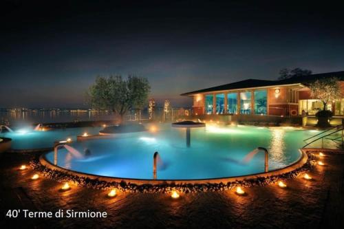 una grande piscina con luci di fronte a un edificio di Garda Sailor’s House a Garda