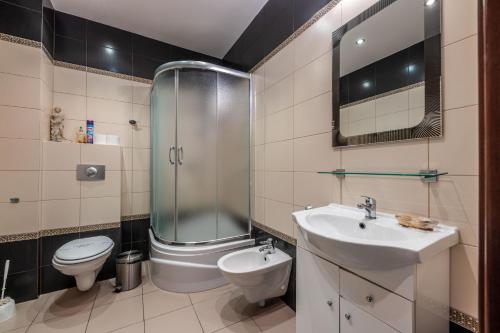 a bathroom with a shower and a toilet and a sink at Victus Apartamenty, Apartament Walor in Sopot