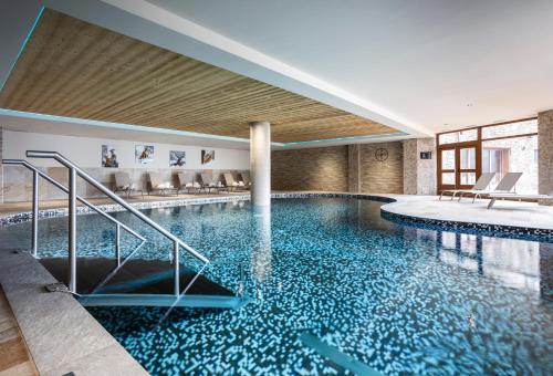 a swimming pool with blue water in a building at Résidence Daria-I Nor by les Etincelles in L'Alpe-d'Huez