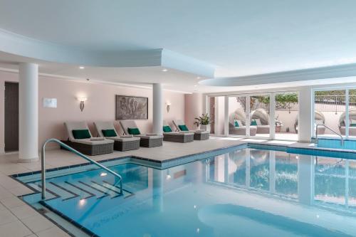 una piscina en un hotel con sillas y un sofá en Hotel Pienzenau Am Schlosspark, en Merano