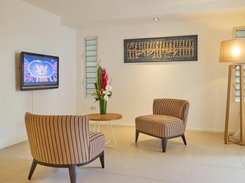 a living room with two chairs and a table with a tv at Le Beachclub in Pereybere