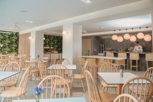 a restaurant with tables and chairs and a chef in the background at Ammos Beach Seaside Luxury Suites Hotel in Olympiaki Akti