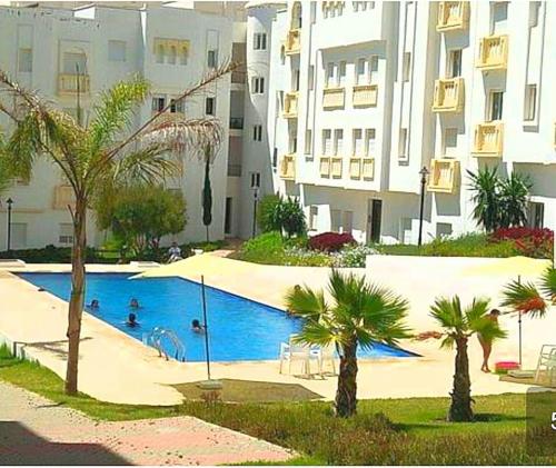 una piscina con palme di fronte a un edificio di chic appart vue sur piscine a Tangeri
