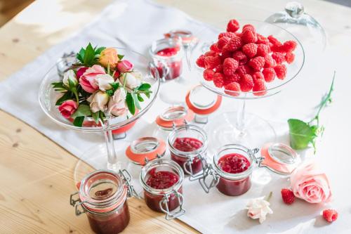 a table topped with two bowls of strawberries and flowers at Hotel Pienzenau Am Schlosspark in Merano