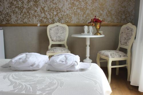 a bedroom with two chairs and a bed with white sheets at Borjomi Classic Hotel in Borjomi