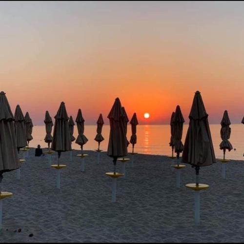 a group of umbrellas on a beach with the sunset at Free Beach Holiday Home in Monte Nai