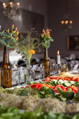 a table topped with a pizza with vegetables and flowers at First Hotel Statt Örnsköldsvik in Örnsköldsvik