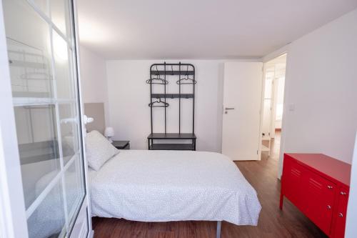 een slaapkamer met een wit bed en een rode dressoir bij Casa das 3 Andorinhas in Olhão