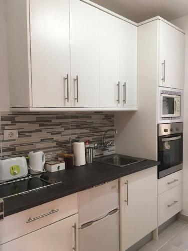 a kitchen with white cabinets and a sink at #Ocean view studio #WIFI in Icod de los Vinos