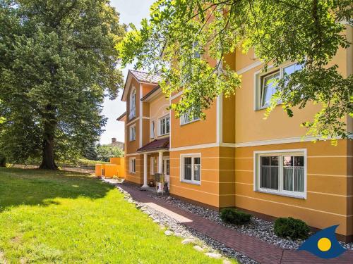 un edificio amarillo con un patio delante en Parkresidenz "Zwei Linden" App 02 "Enjoy" en Heringsdorf
