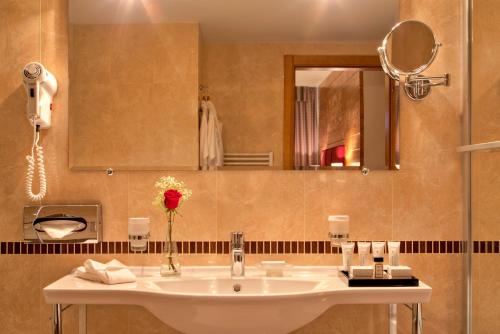 a bathroom with a sink and a mirror at Kempinski Hotel Grand Arena Bansko in Bansko