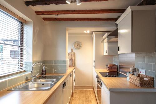 a kitchen with white cabinets and a sink and a window at The Stable, Yew Tree Farm Holidays, Tattenhall, Chester in Chester