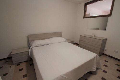 1 dormitorio con cama blanca y ventana en Casetta delle Arti, en Mondragone