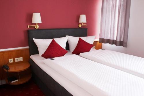 two beds with red and white pillows in a room at Hotel Gasthof Adler in Ulm