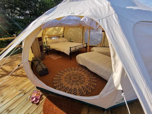 - une tente sur une terrasse avec un lit dans l'établissement Glamping La Petite Lande, à Pierrefiche