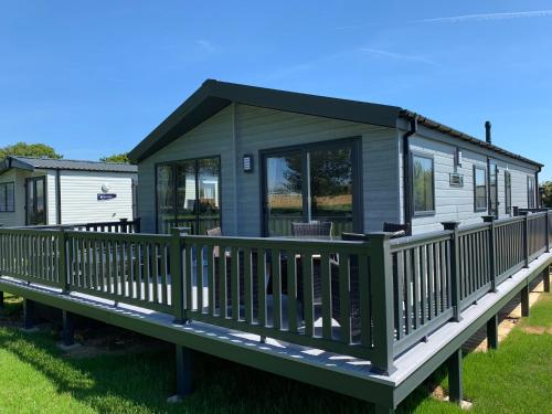 a green modular house with a porch on a deck at St Helens Coastal Resort in Saint Helens