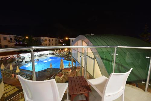 a balcony with chairs and a swimming pool at night at Belcehan Hotel in Oludeniz