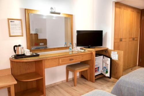 a room with a desk with a mirror and a television at Belcehan Hotel in Oludeniz