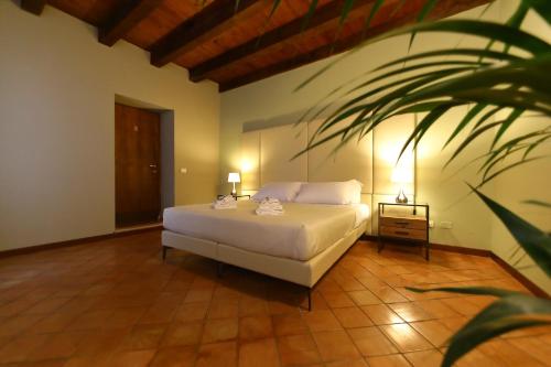 ペスキエーラ・デル・ガルダにあるOsteria Luxury Apartmentsの白いベッドと植物が備わるベッドルーム1室が備わります。