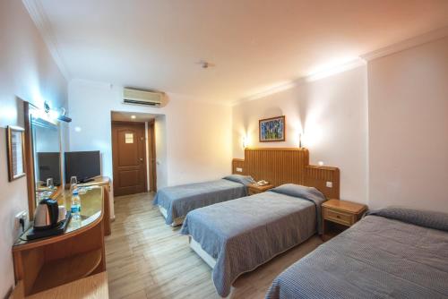 a hotel room with two beds and a television at Belcehan Hotel in Oludeniz