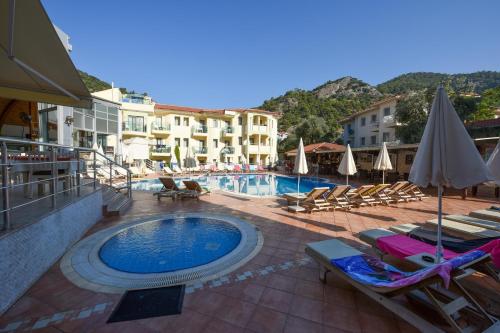 a swimming pool in a resort with chairs and umbrellas at Belcehan Hotel in Oludeniz