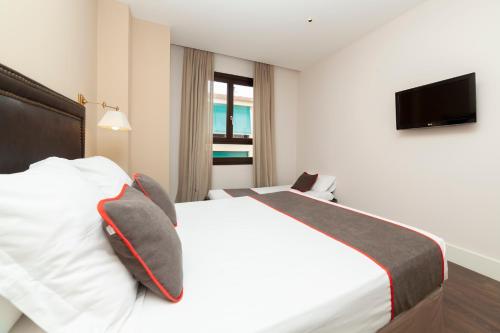 a hotel room with a bed with pillows and a television at Hotel Altora in Tomelloso