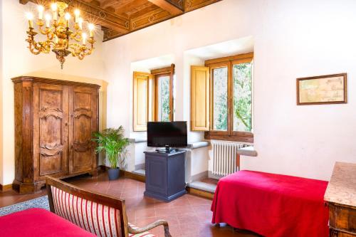 a living room with a table and a television and a chandelier at Villa Pitiana in Donnini