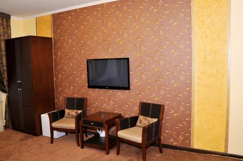 a room with two chairs and a table with a tv on a wall at Totem Hotel in Shymkent