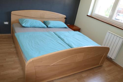 een bed met een houten hoofdeinde en blauwe lakens bij Apartment Olivia in Čiginj
