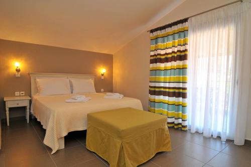 a bedroom with a white bed and a colorful curtain at Ntinas Filoxenia Hotel & Spa in Skala Potamias