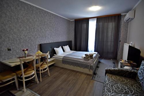 een slaapkamer met een bed, een tafel en een bank bij City Apartments in Velingrad