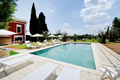 a swimming pool with chairs and a house at Agriturismo Santa Chiara in Alezio