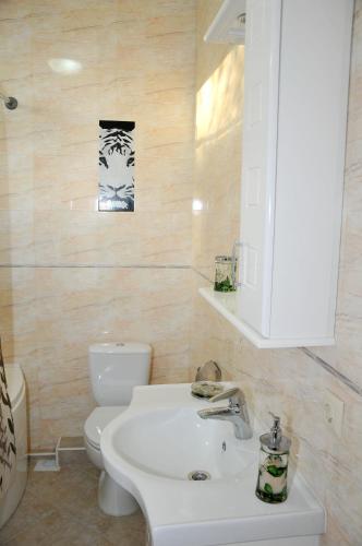 a bathroom with a white sink and a toilet at Totem Hotel in Shymkent
