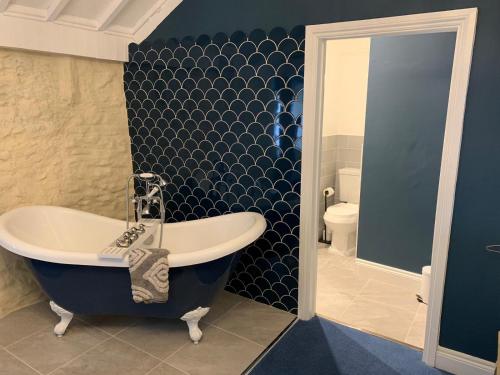 a blue bathroom with a tub and a toilet at The Mendip Inn in Binegar