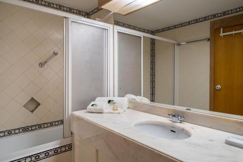 a bathroom with a sink and a large mirror at BmyGuest - Quinta do Lago Garden Apartment in Almancil