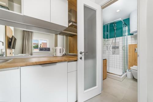 a kitchen with white cabinets and a sink and a toilet at Poseidon Deluxe перша лінія з басейном in Odesa