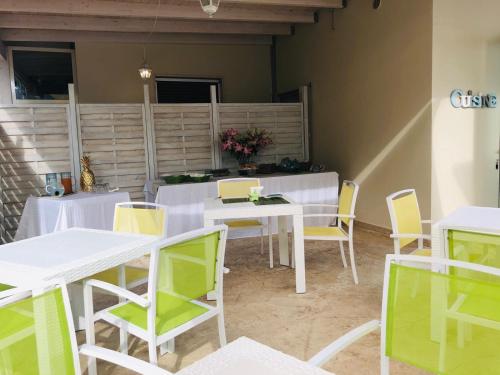 a dining room with white tables and yellow chairs at Villa dei Ginepri in Gallipoli