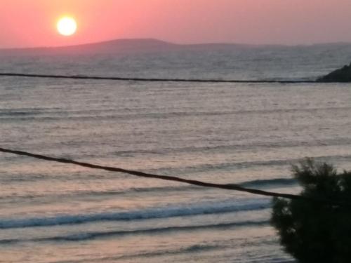 a sunset over the ocean with a beach at Infinity Apartments in Naxos Chora