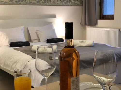 a bottle of wine sitting on a table with two glasses at Mandula Apartman in Cegléd