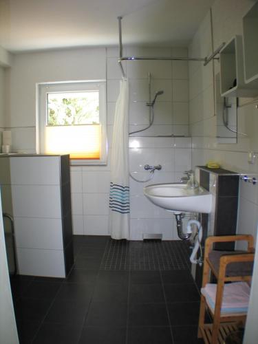 La salle de bains blanche est pourvue d'un lavabo et d'une fenêtre. dans l'établissement Ferienwohnung in Waldrandlage, à Zierenberg