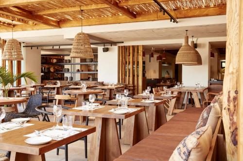 a restaurant with wooden tables and chairs and chandeliers at The Syntopia Hotel - Adults Only in Adelianos Kampos