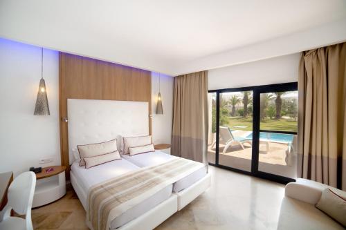 a bedroom with a large white bed and a balcony at TUI BLUE Manar in Hammamet