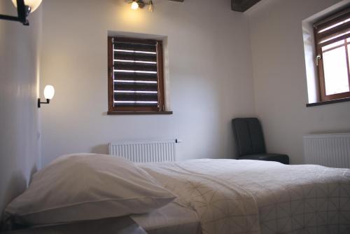 a white bedroom with a bed and a window at Chata Diana in Vítkovice