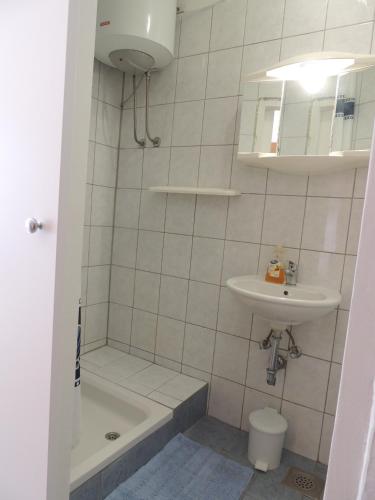a bathroom with a sink and a tub and a toilet at Apartments Barcarola in Pag